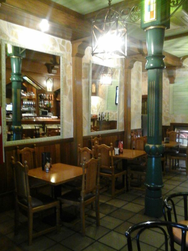 Un restaurante con mesas y sillas y un pilar verde.