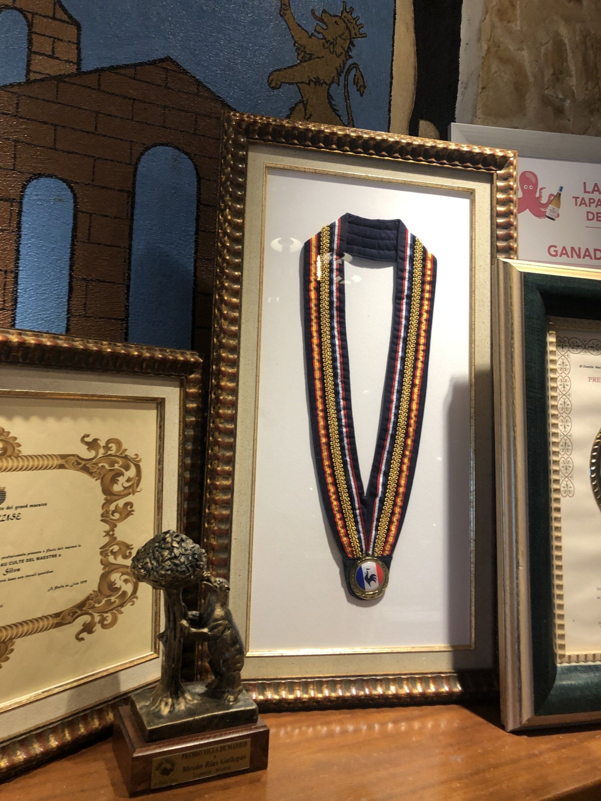 Una medalla enmarcada se encuentra sobre una mesa junto a otros elementos enmarcados.