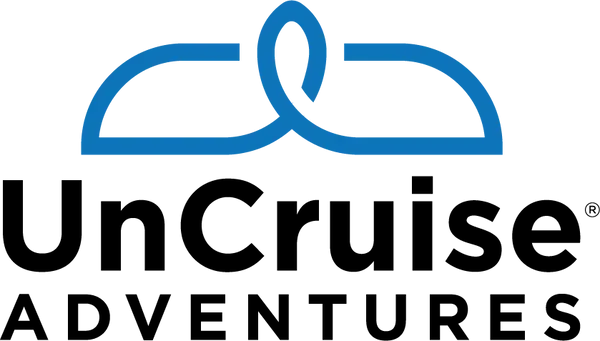 The blue logo for UnCruise Adventures features a stylized bow-shaped icon above the company name in black text.