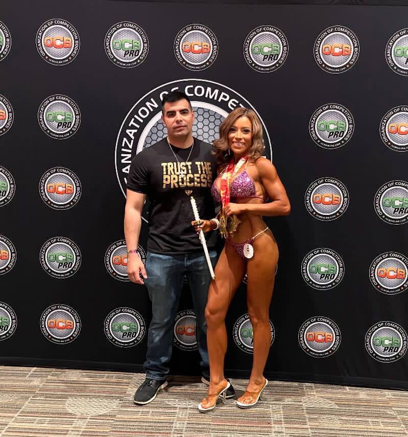 A man and a woman are posing for a picture in front of a wall that says trust the process.
