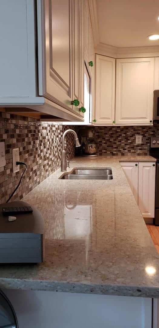 A kitchen with granite counter tops , stainless steel appliances , and white cabinets.