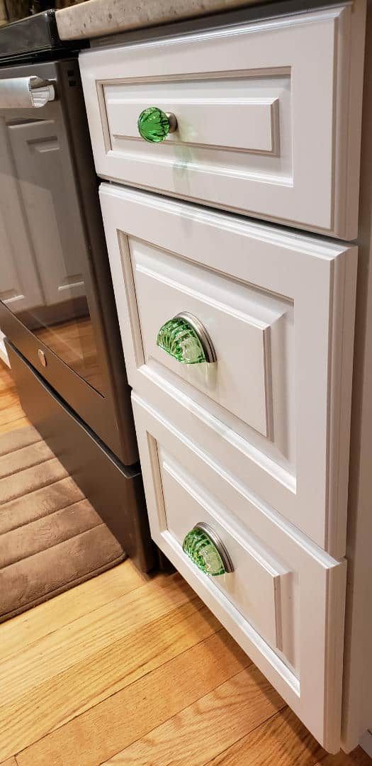 A kitchen with white cabinets and green handles on the drawers.