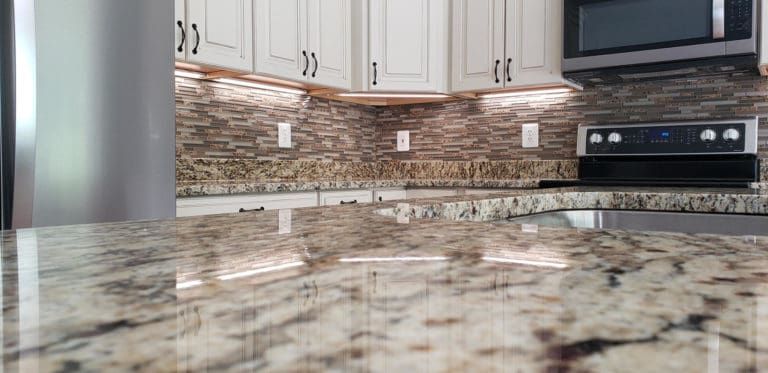 A kitchen with granite counter tops , stainless steel appliances , and white cabinets.