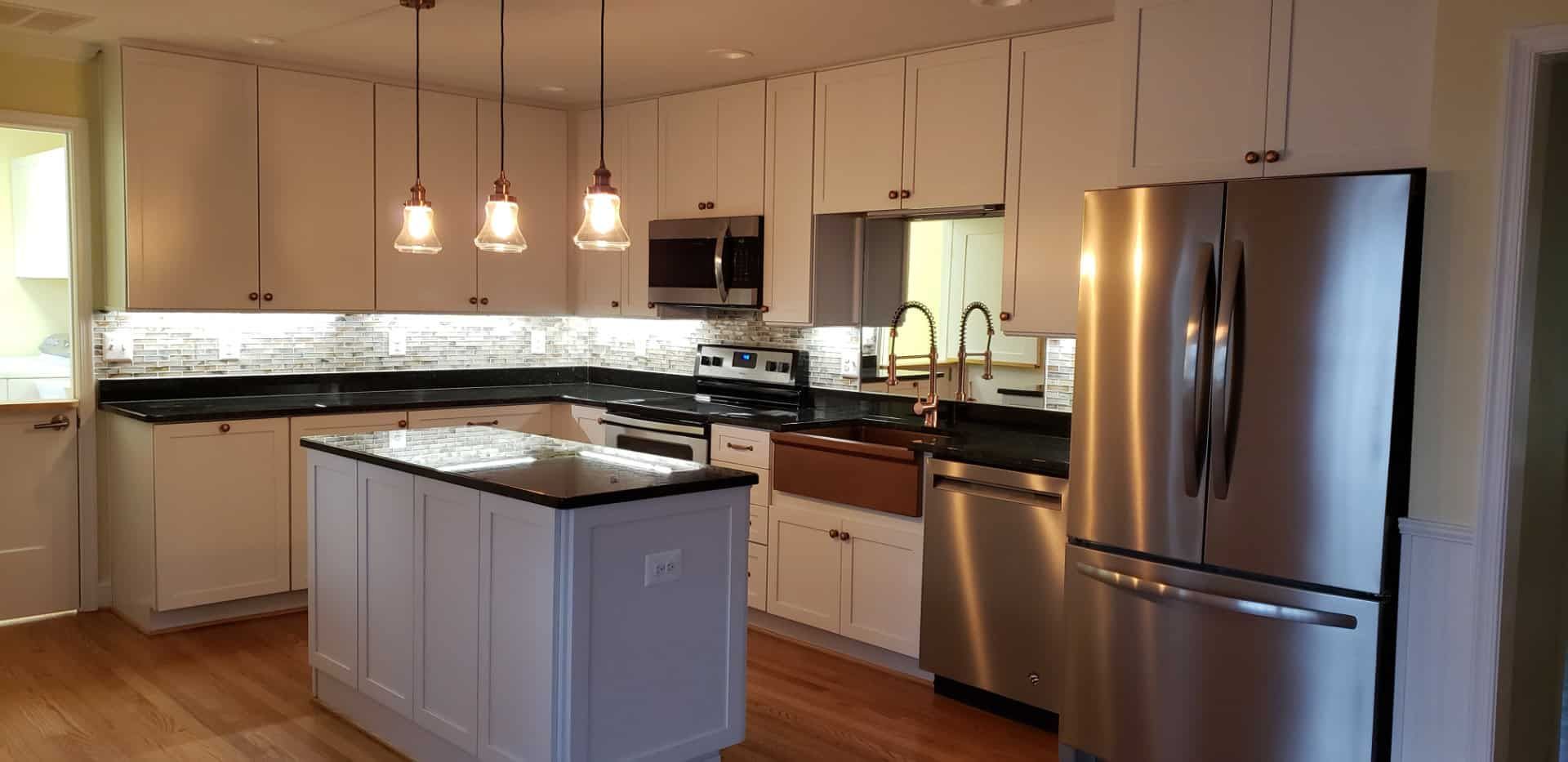 A kitchen with white cabinets , stainless steel appliances and a large island.