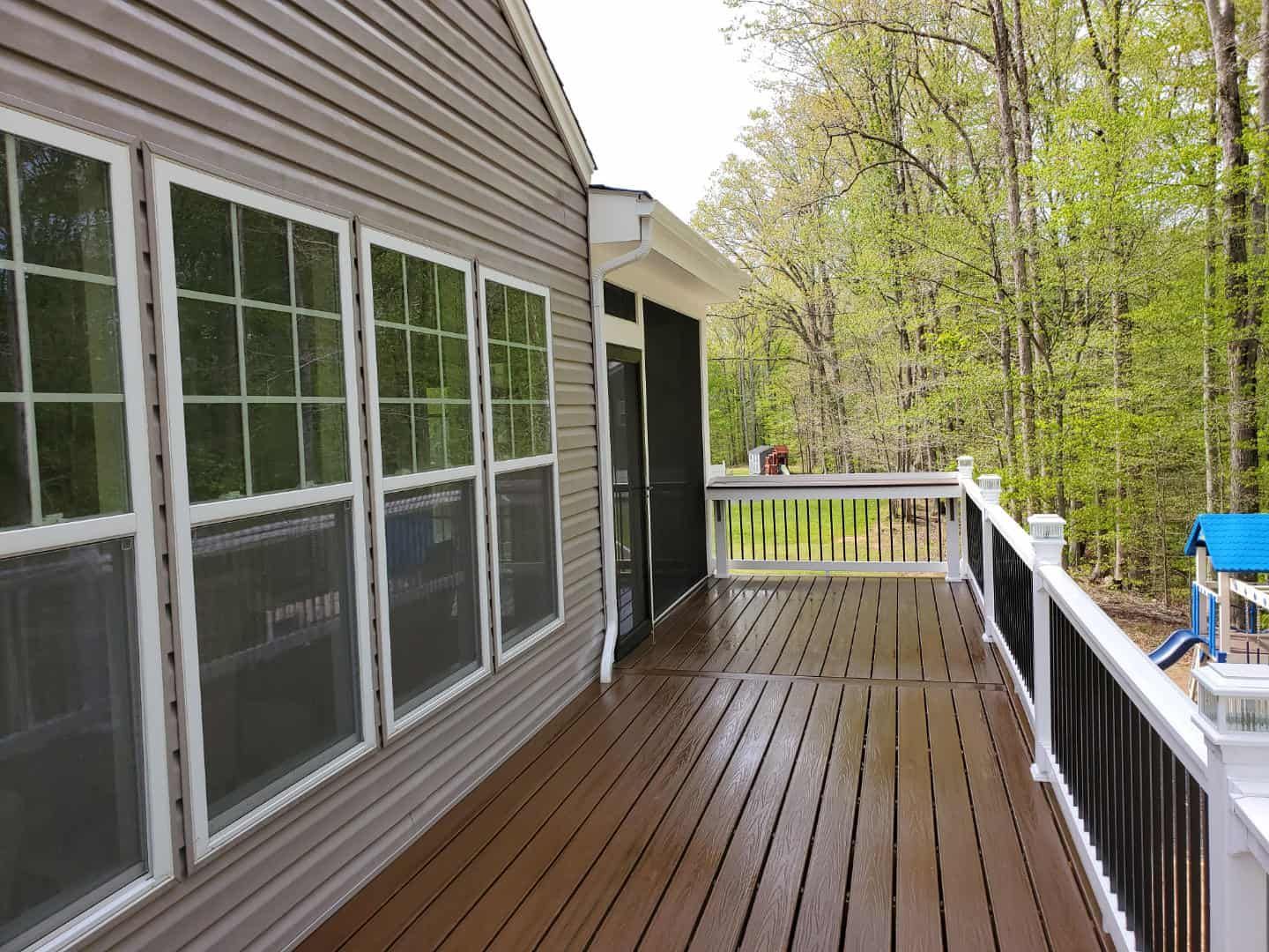 A large deck with lots of windows and trees in the background