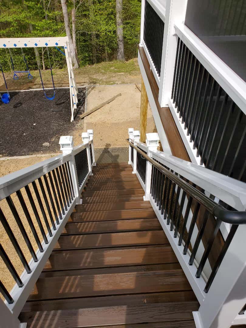 A set of stairs leading up to a deck with a playground in the background.