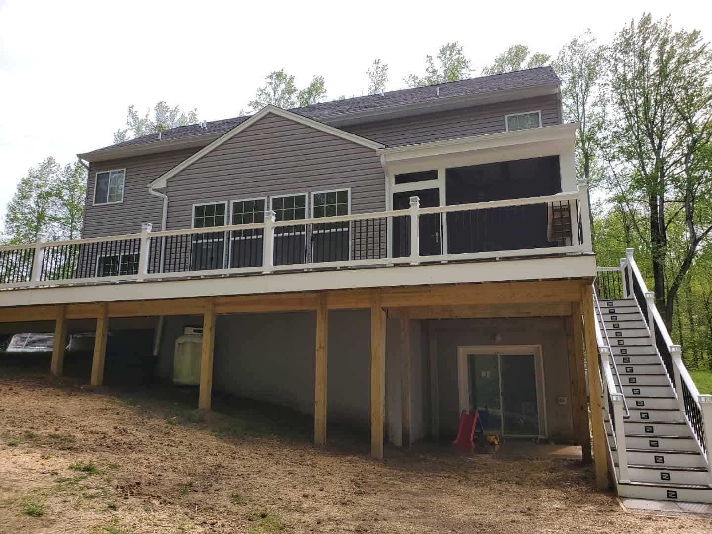 The back of a house with a large deck and stairs.
