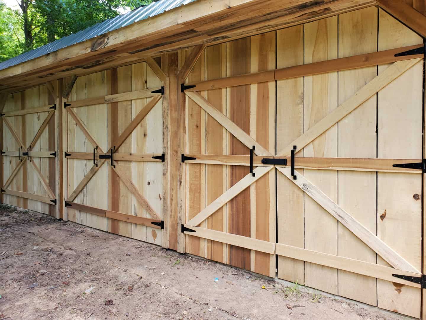 A wooden barn with a metal roof and wooden doors