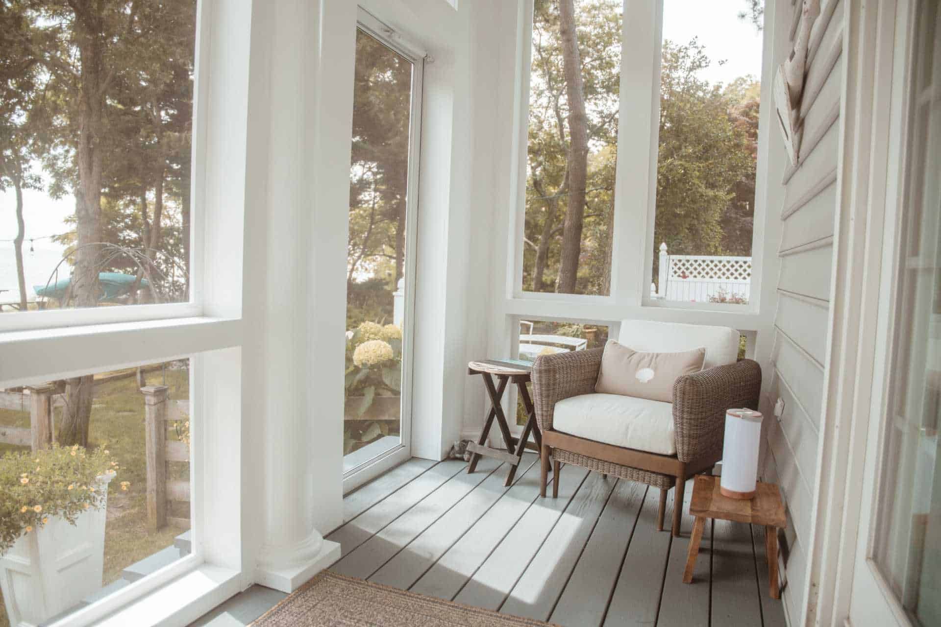 A screened in porch with a chair and a table.