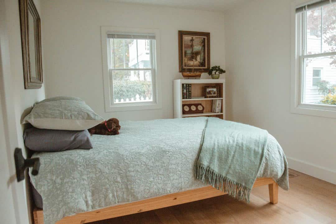A bedroom with a bed , bookshelf , and window.