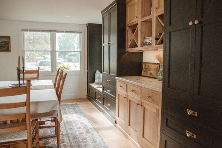 A dining room with a table and chairs and black cabinets.