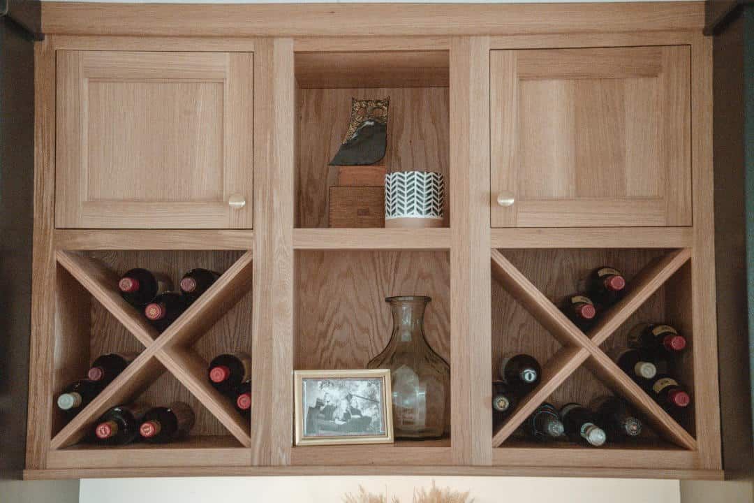 A wooden wine rack with bottles of wine and a picture on the shelf.