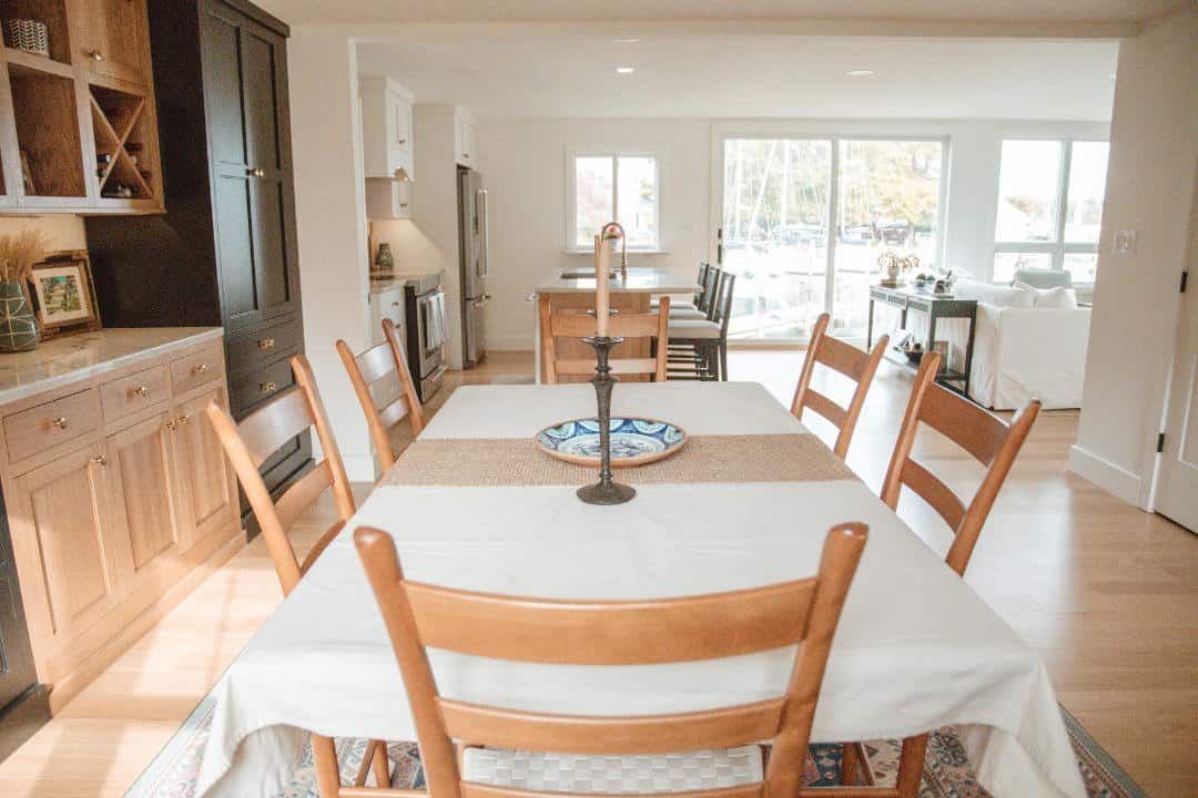 A dining room table with a white tablecloth and wooden chairs.