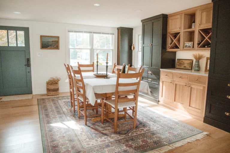 A dining room with a table and chairs and a rug.