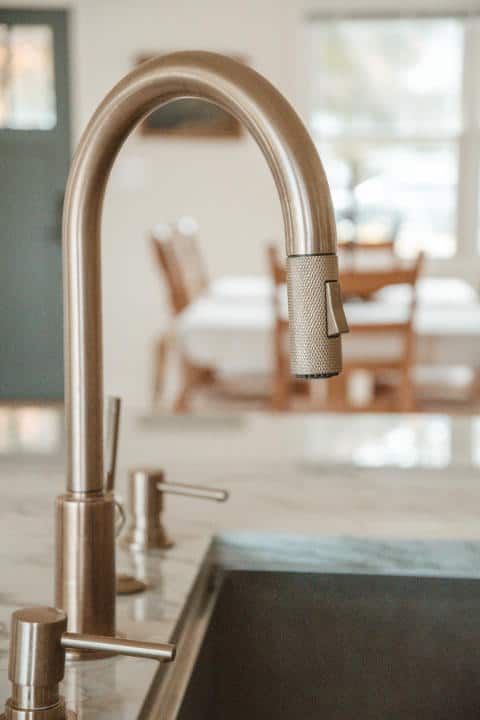 A close up of a kitchen sink with a faucet and soap dispenser.