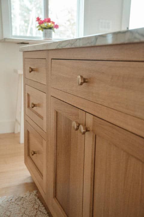 A kitchen with wooden cabinets and drawers and a marble counter top.