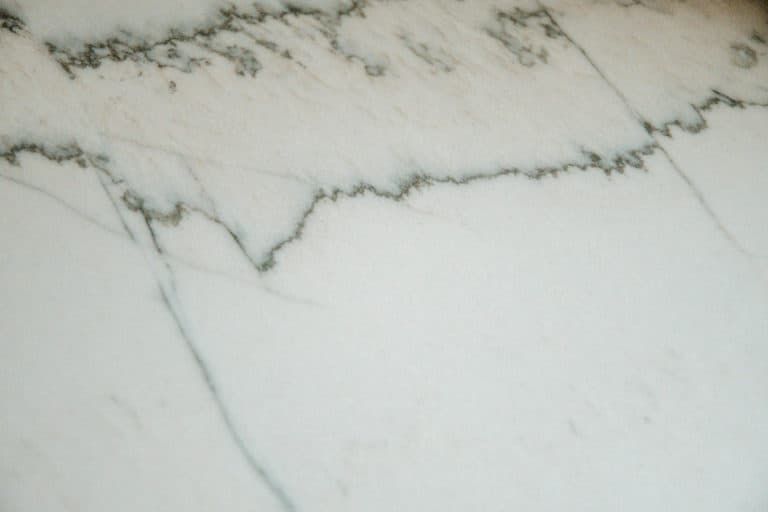 A close up of a white marble counter top with black veins.