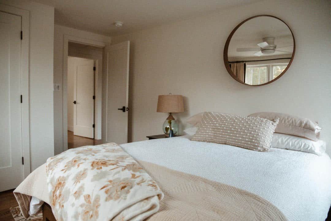 A bedroom with a bed , mirror and lamp.