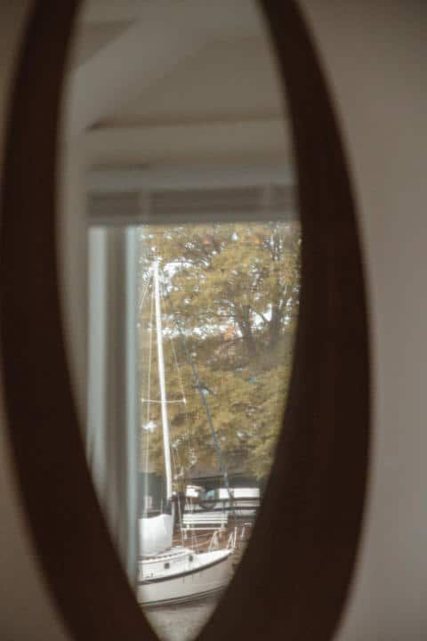 A boat is reflected in a mirror next to a window.