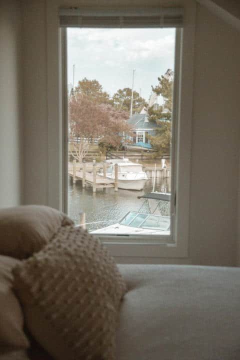 A living room with a couch and a window overlooking a body of water.