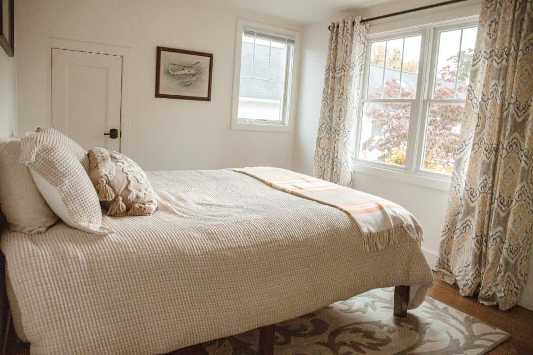 A bedroom with a bed , window and rug.