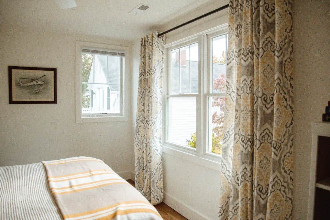 A bedroom with a bed , two windows and a fireplace.
