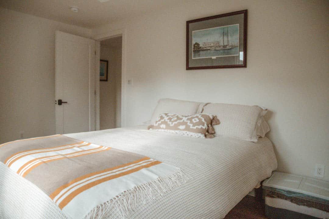 A bedroom with a bed and a picture on the wall above it.