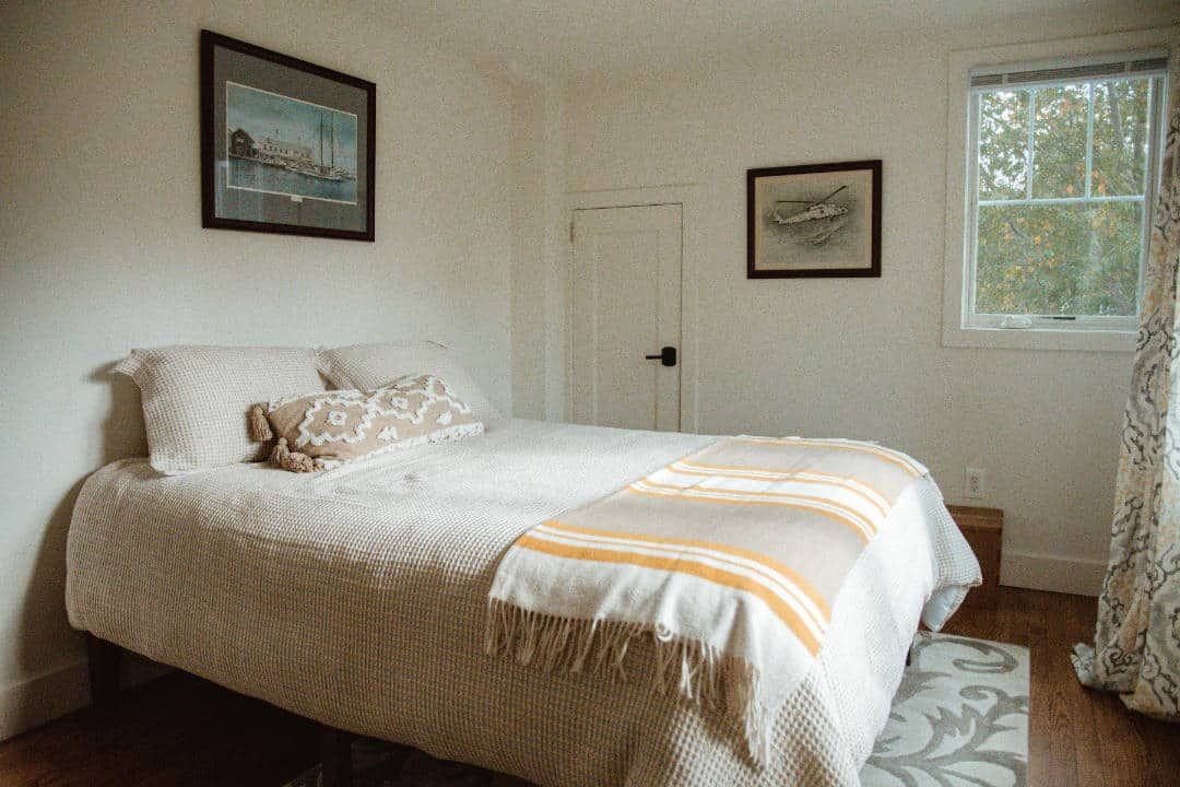 A bedroom with a bed and a window with a picture on the wall.