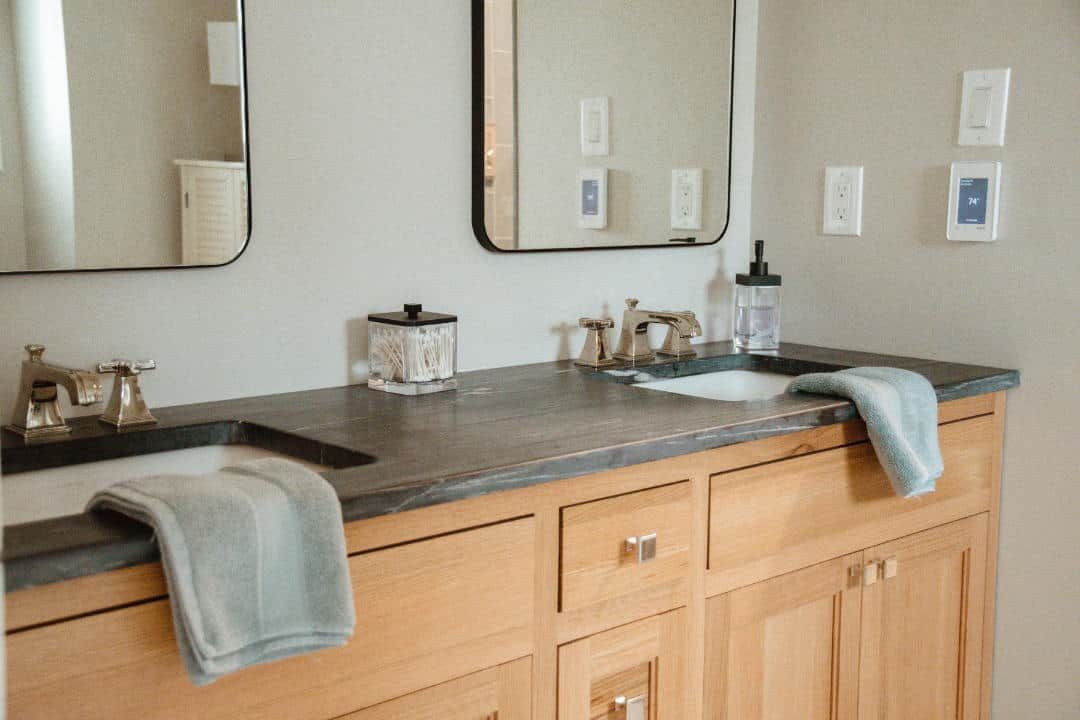 A bathroom with two sinks , a mirror , and wooden cabinets.