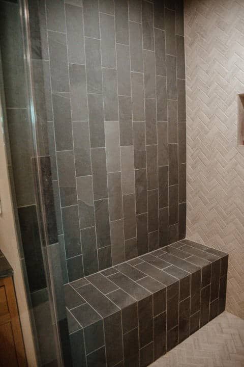 A shower with a bench in it and a glass door.