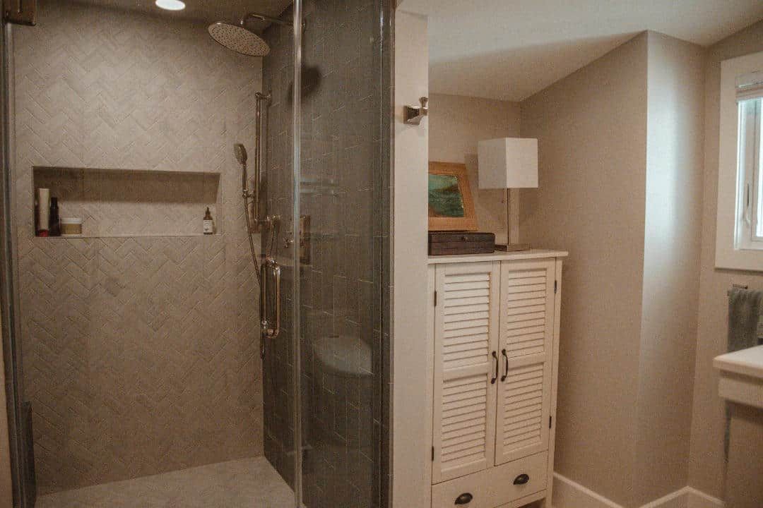 A bathroom with a walk in shower and a cabinet.