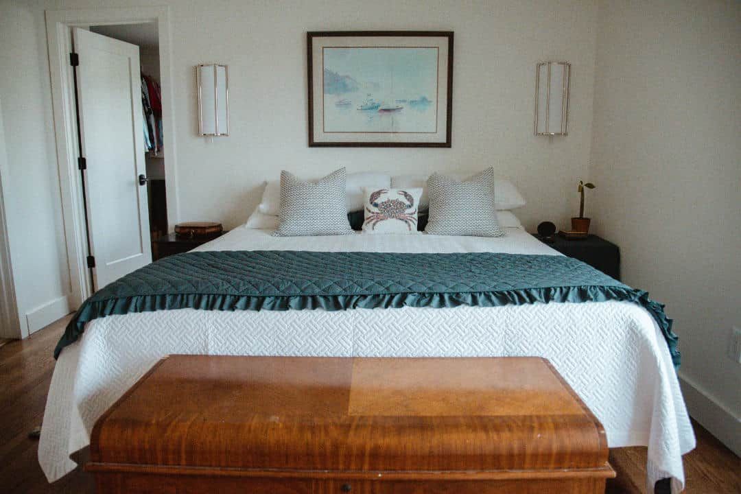 A bedroom with a bed , a trunk , and a picture on the wall.