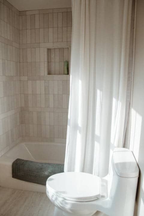 A bathroom with a toilet , bathtub and shower curtain.