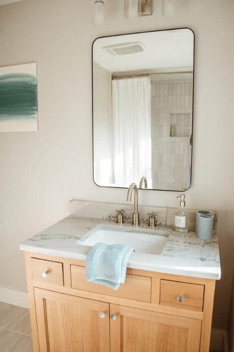 A bathroom with a sink , mirror and cabinets