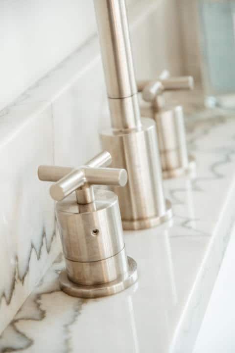 A close up of a bathroom sink with stainless steel faucets.