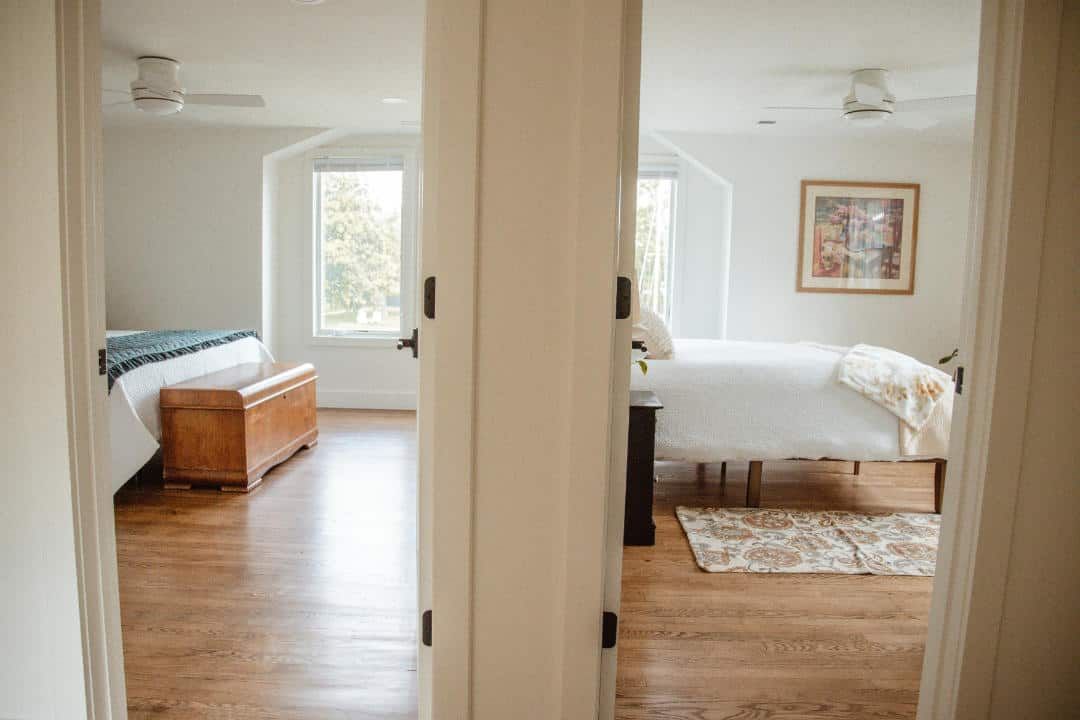 A bedroom with two beds , a dresser , and a window.