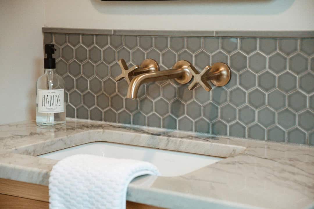 A bathroom sink with a bottle of soap and a towel on the counter.