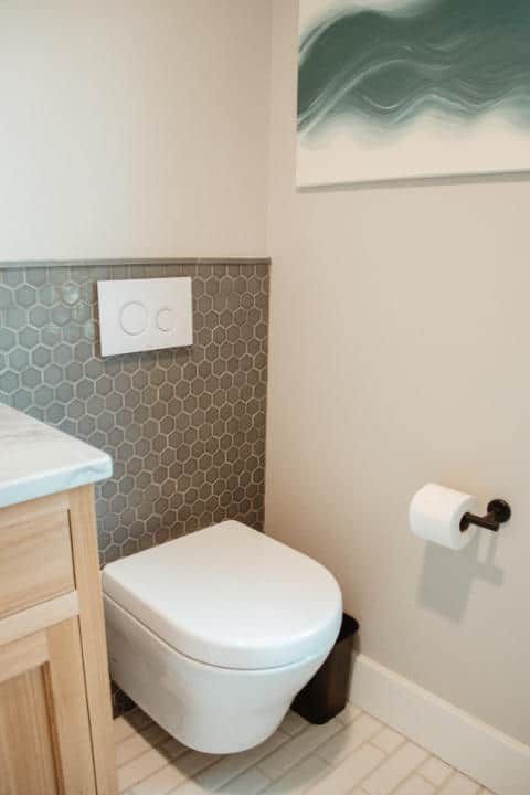 A bathroom with a toilet , sink and toilet paper.