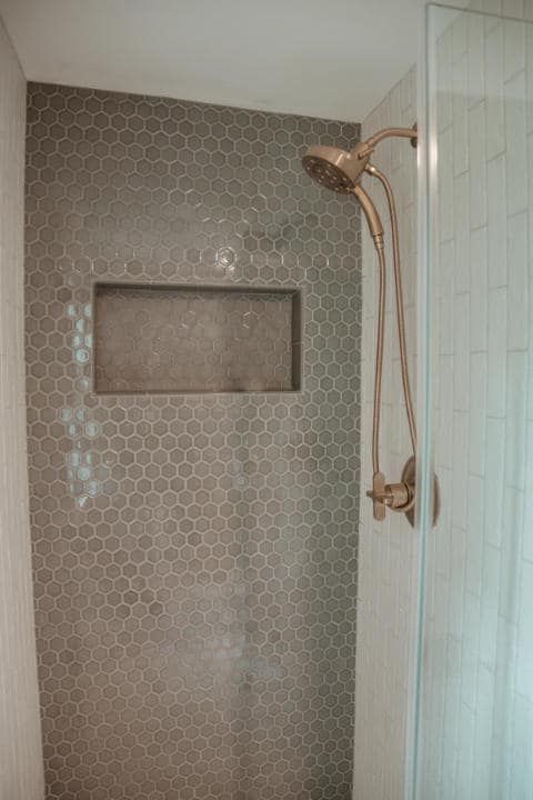 A shower with a shower head and a niche in the wall.