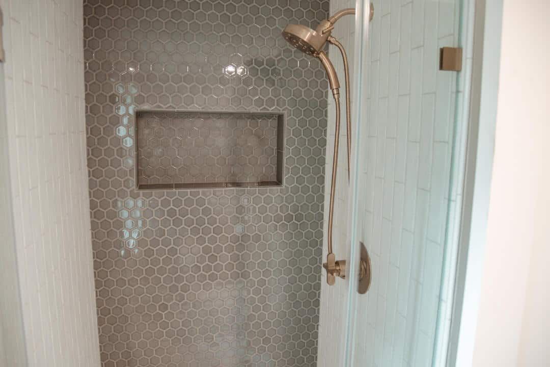A shower with a glass door and a shower head.