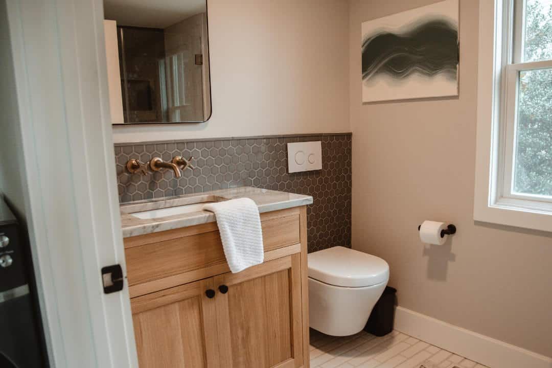 A bathroom with a sink , toilet , mirror and window.