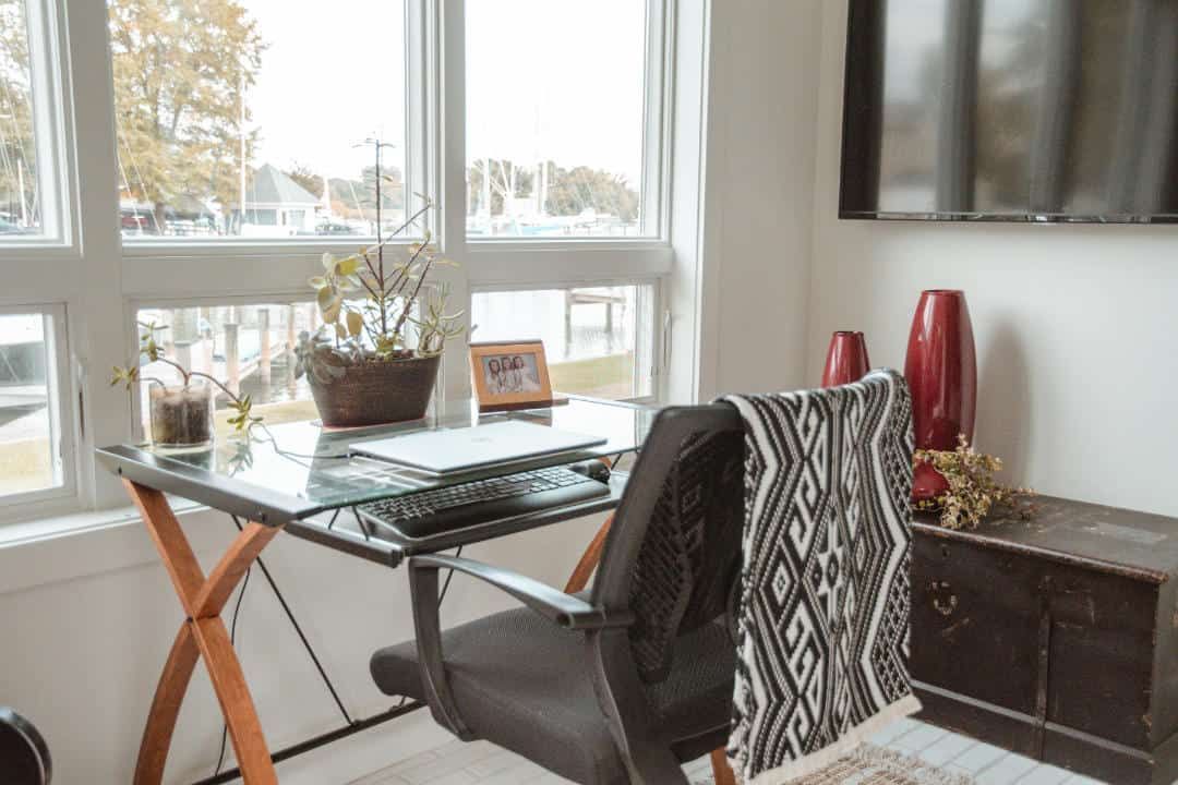 A home office with a desk , chair and television.