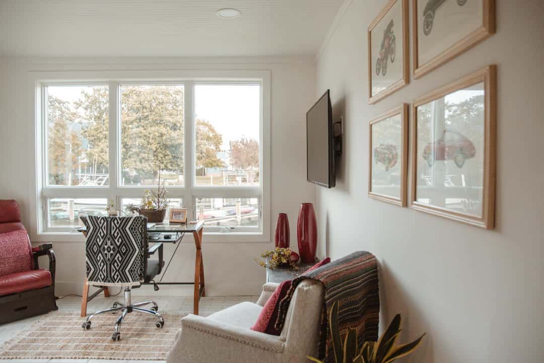 A living room with a desk , chair , and television.