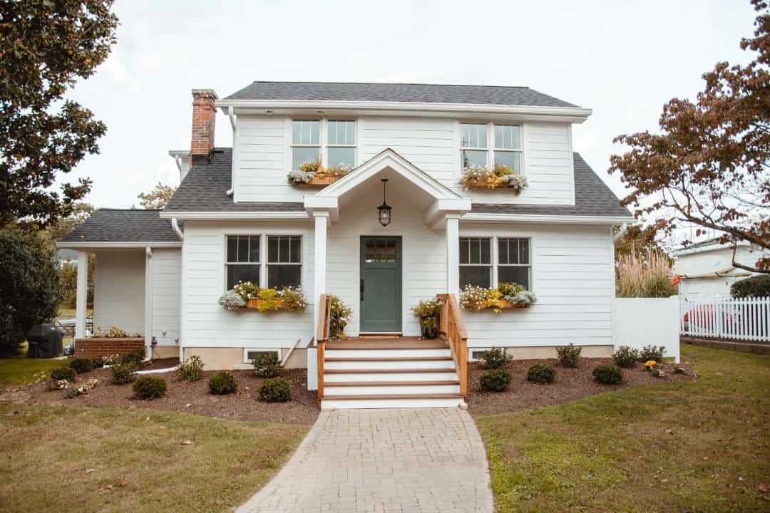 A white house with a green door and a walkway leading to it.