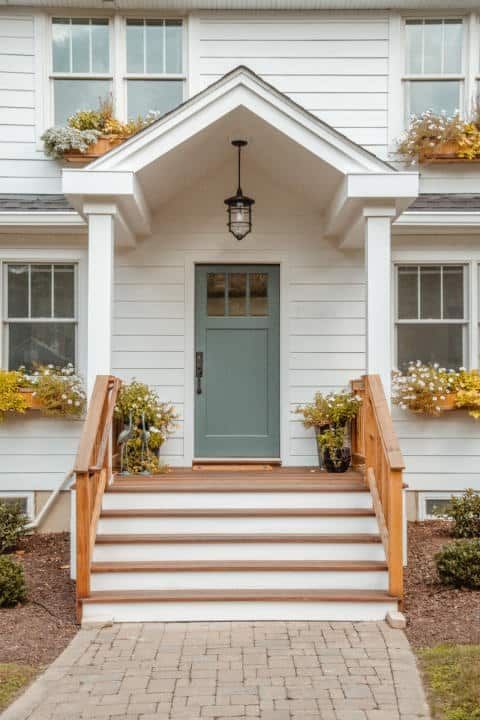 A white house with a blue door and stairs