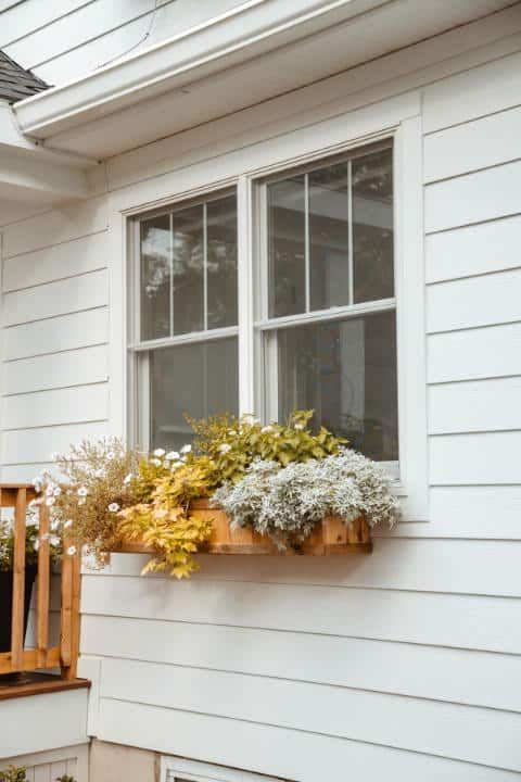 A white house with a window box filled with flowers.