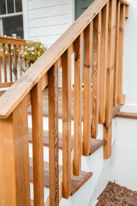 A wooden railing on a set of stairs leading up to a house