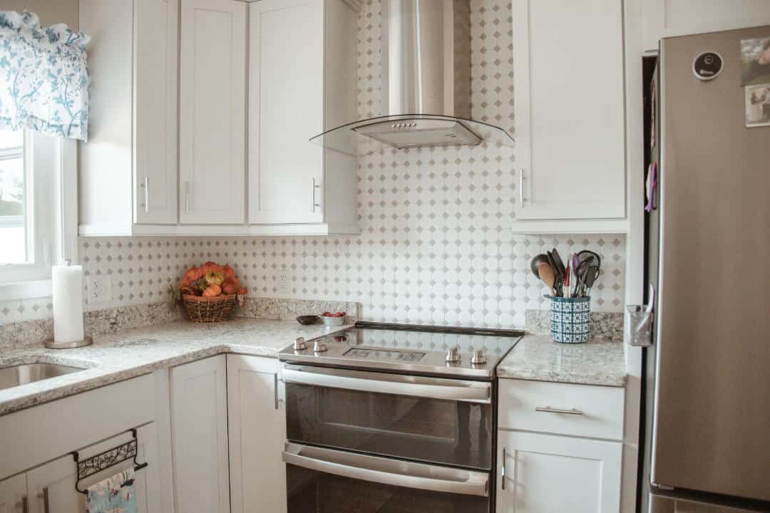 A kitchen with white cabinets , a stove , a refrigerator , and a sink.