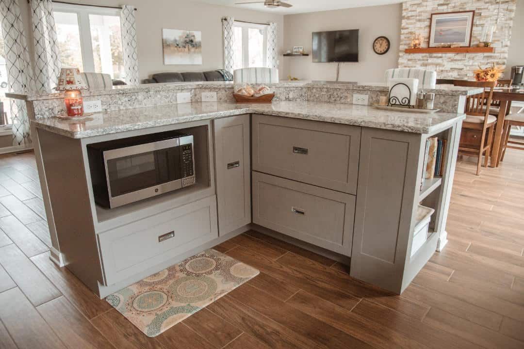 A kitchen with a microwave on the counter and a rug on the floor.
