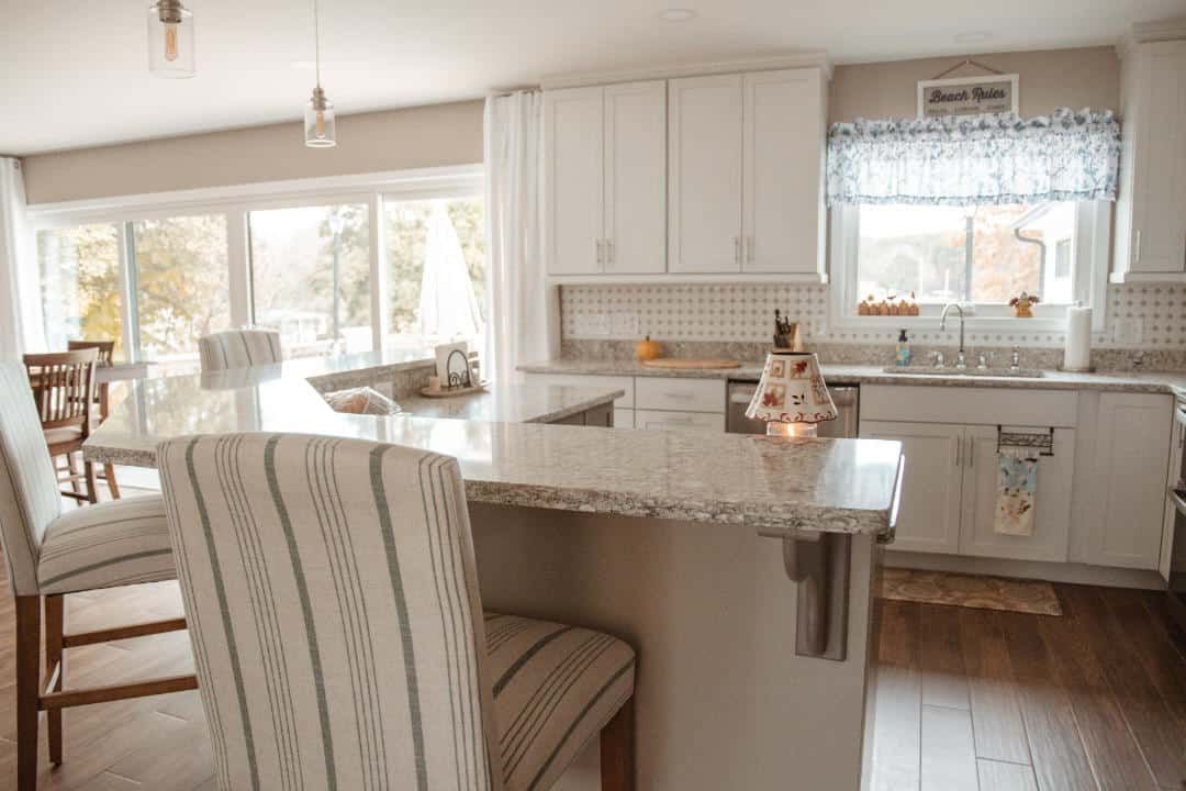 A kitchen with white cabinets , granite counter tops , a table and chairs.
